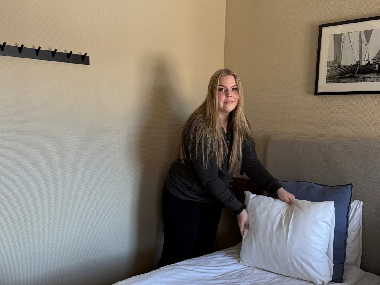 Ung kvinna puffar kudden när hon städar på hotellet