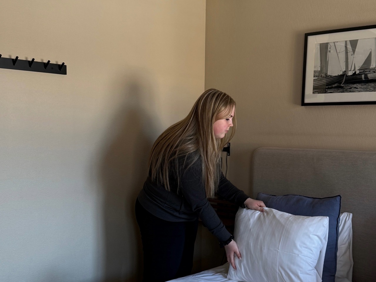 Kvinna puffar kuddar i hotellsäng