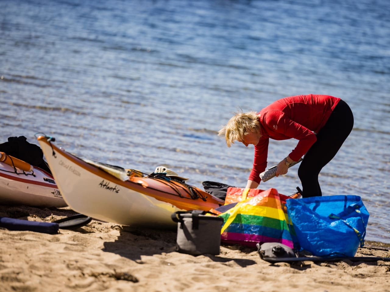 Kvinna som packar sin kajak vid havet i Grebbestad